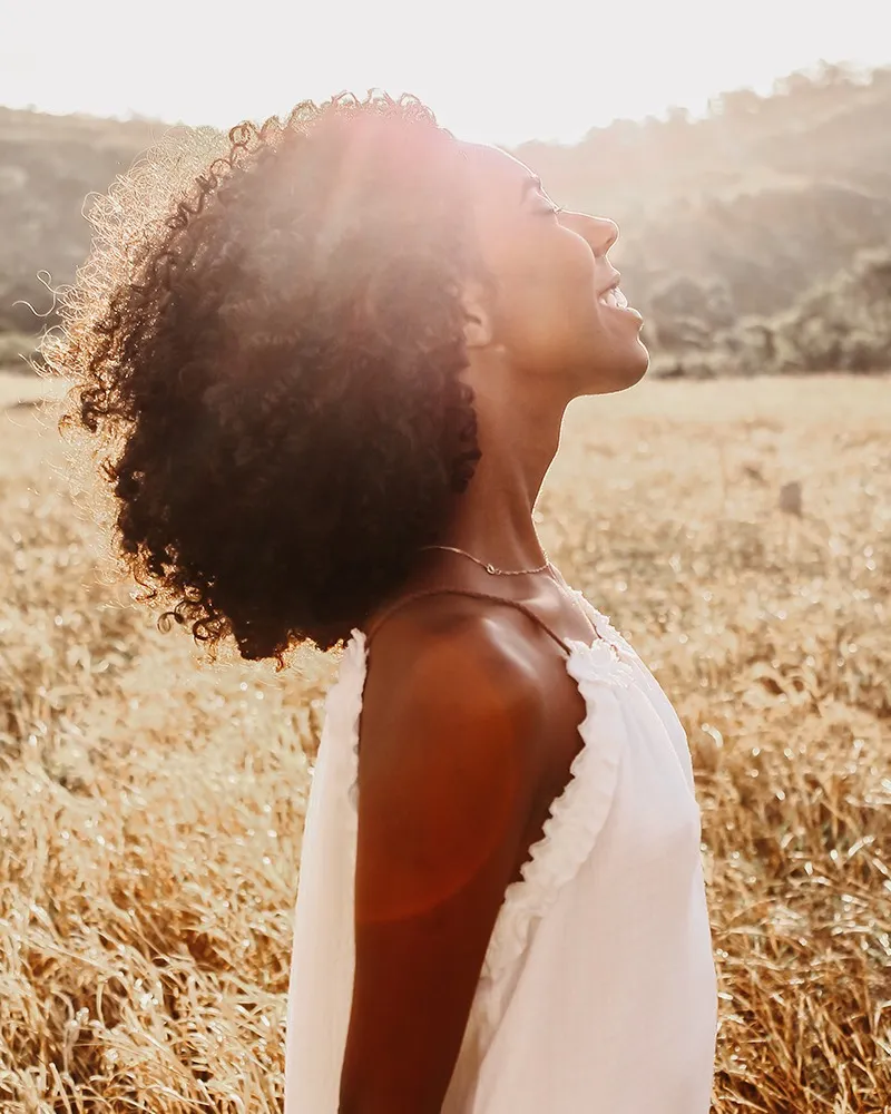 Pretty black woman with closed eyes smiling in a field