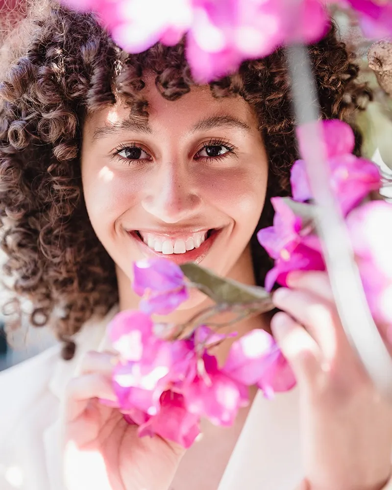 Woman with purple flowers smiling with clear Invisalign trays