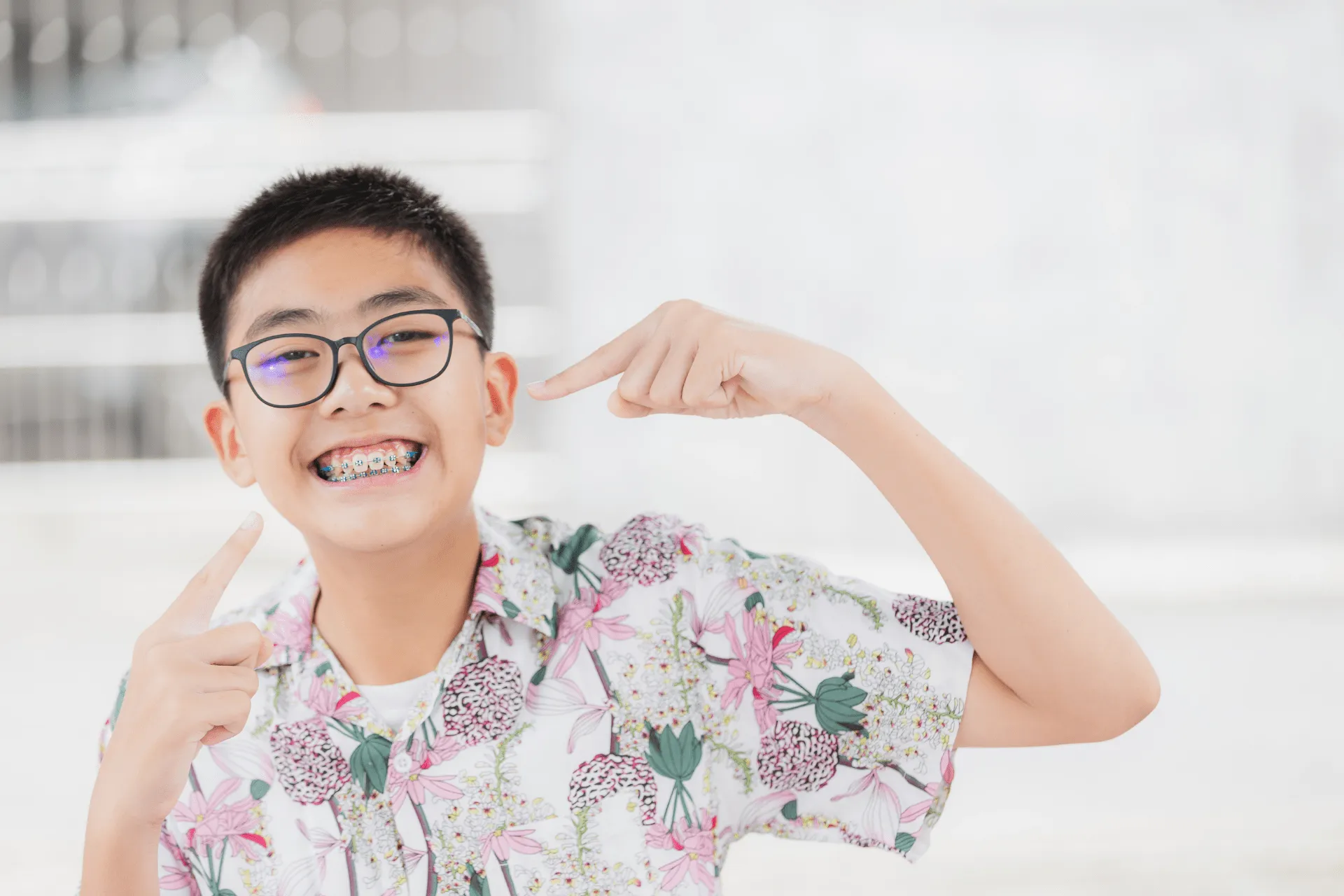child smiling and pointing at his braces