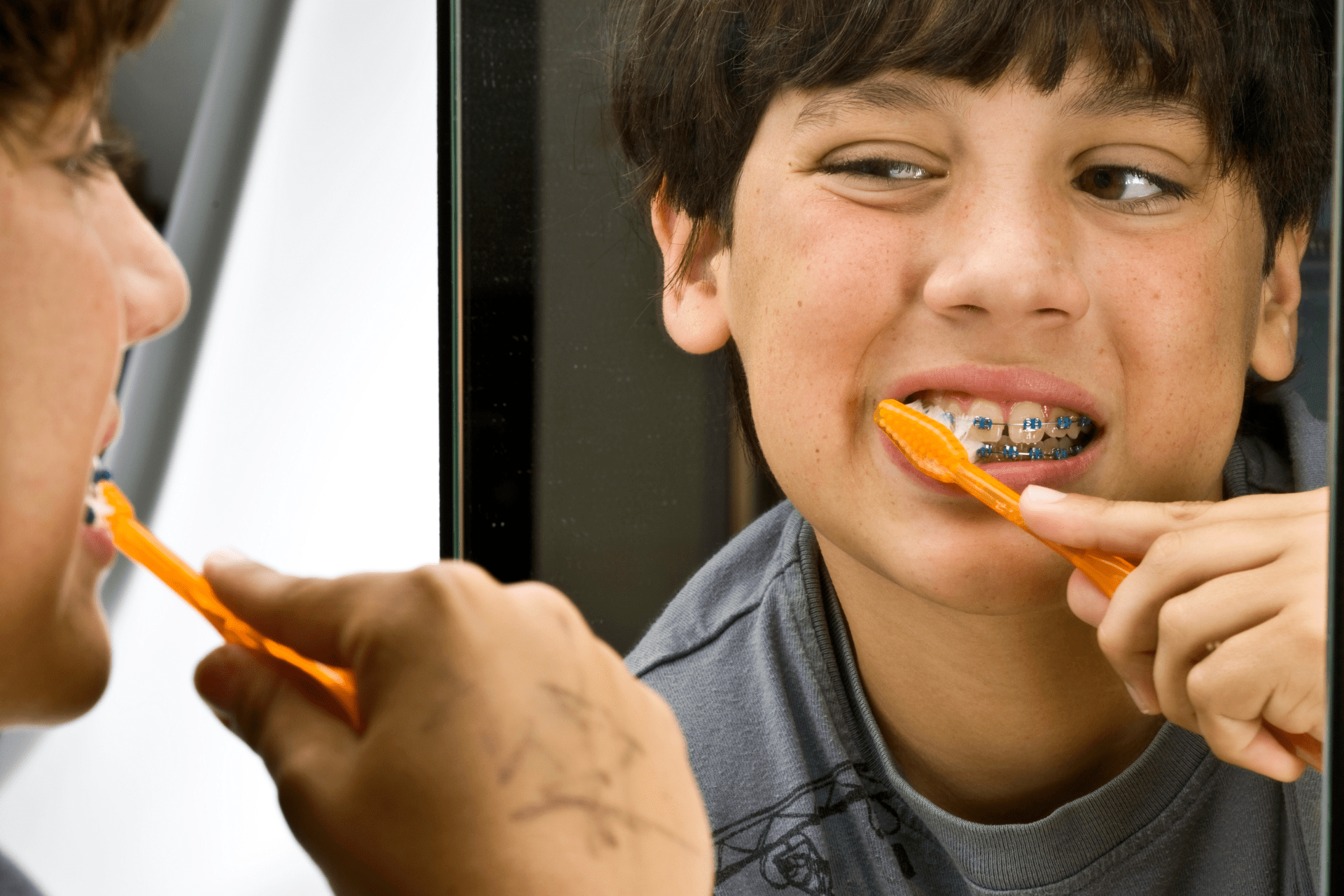 young boy brushing braces with a toothbrush