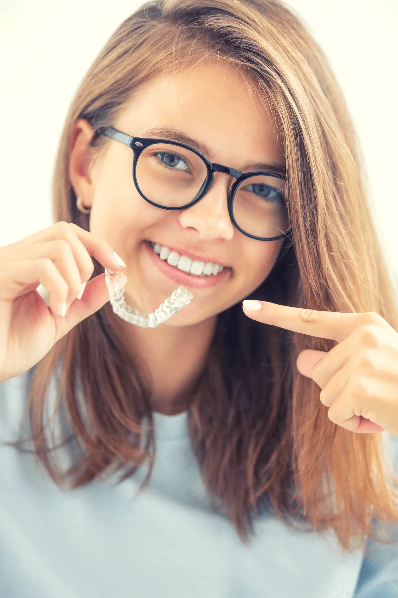 child smiling and pointing at his braces